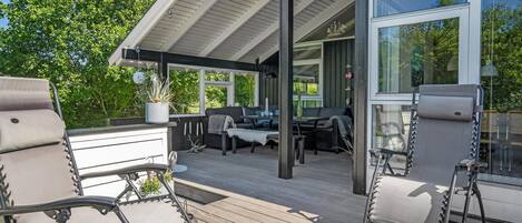 An outdoor deck with seating, a grill, and a potted plant.