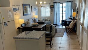 A compact kitchen with a central island, a dining area with a table and chairs, and a living space with a sofa and a TV.