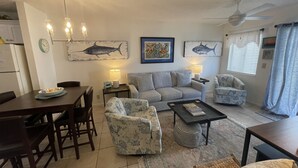 A living room with a sofa, armchairs, a coffee table, and a dining area with chairs and a table.