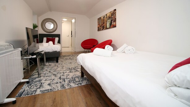 Una habitación de hotel moderna con una cama grande, un escritorio con silla, un radiador y un espejo en la pared.