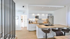 Una cocina moderna con una isla central, taburetes de bar y vistas al área de comedor.