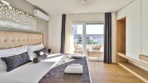 Una habitación de hotel moderna con una cama grande, un ventilador de techo y vistas al balcón exterior.