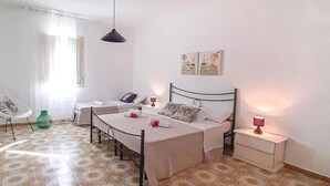 A bedroom with a bed, bedside tables, a chair, and a hanging light fixture. - 1 bedroom beach front home in Siracusa (Siracusa)