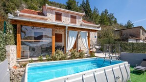 Una villa con piscina, muros de piedra y contraventanas de madera.