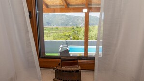 Una habitación con un amplio ventanal que da a una piscina y montañas.
