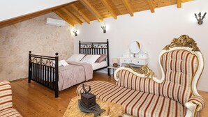 Un dormitorio con cama, una silla, una mesita y un aparador.