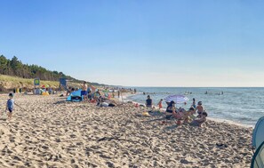 Een strand met mensen die ontspannen en zonnebaden, parasols en strandstoelen.