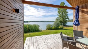 Un pontile di legno con vista su un lago, immerso nel verde e sotto un cielo sereno.