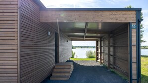 Un'area esterna coperta con un patio in legno che conduce a un garage, vista su un lago e un cartello con il numero 10.