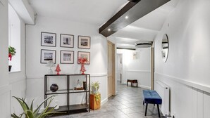 A hallway with a white wall, a wooden bench, a glass shelf with decorative items, and framed pictures on the wall. - Pet friendly apartment in Esbjerg V (Esbjerg V)