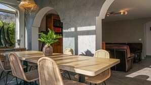 A dining area with a wooden table, wicker chairs, a potted plant, and a bookshelf. - Amazing home in AGDE with WiFi (AGDE)