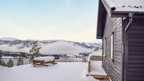 A wooden cabin with a snow-covered deck and a view of a lake and mountains. - Beautiful home in Vrådal with sauna (Vrådal)