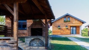 A wooden cabin with a stone fireplace, a covered porch, and a well-maintained lawn. - Stunning home in Slunj with swimming pool (Slunj)