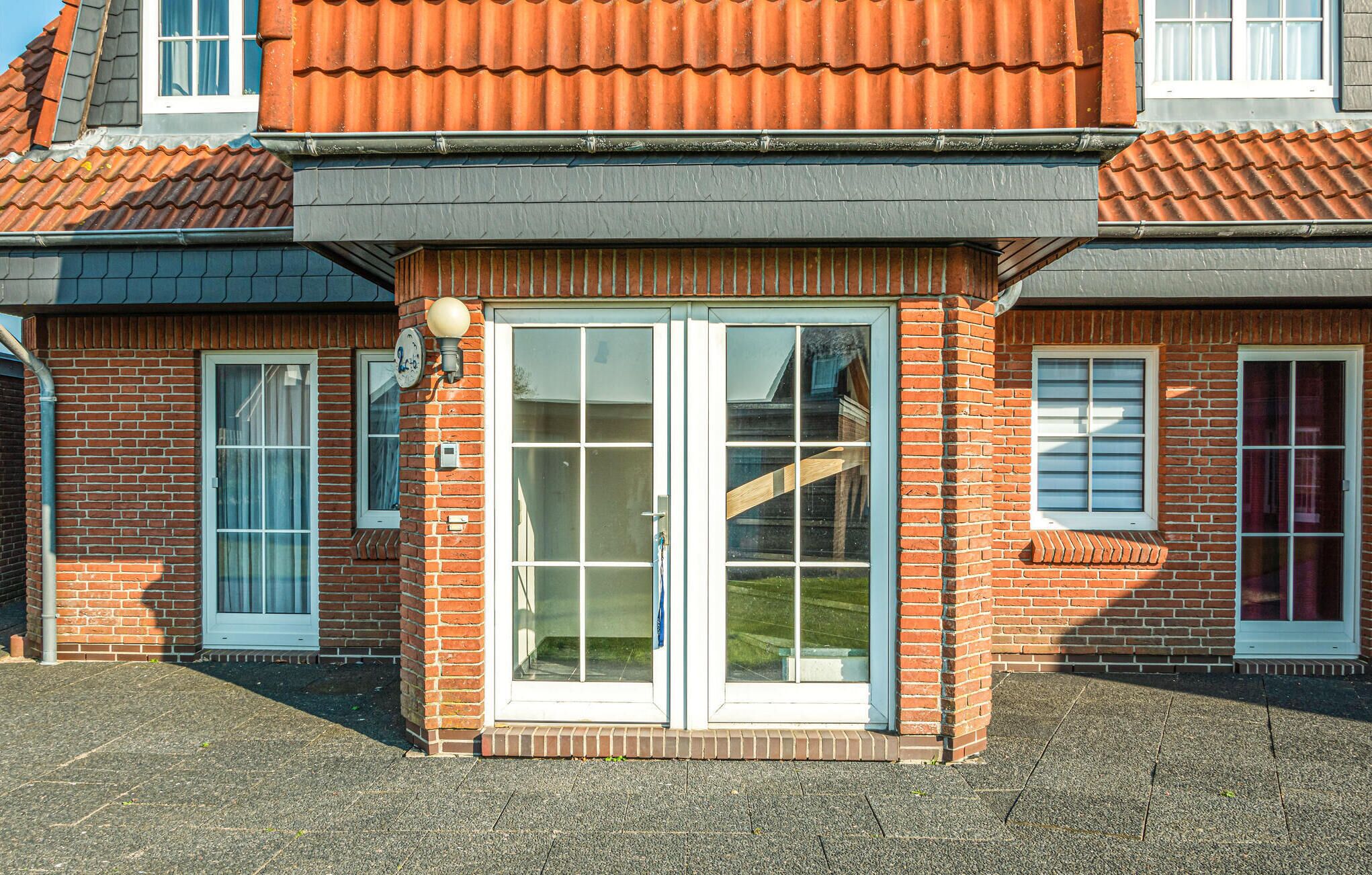 A two-story building with a brick facade, large glass sliding doors, and a red-tiled roof.