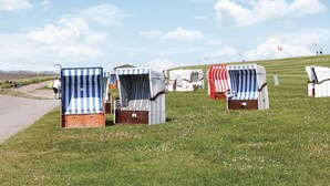 A row of beach huts with striped awnings, arranged on a grassy field with a clear sky. - Gorgeous apartment in Friedrichskoog OT Frie (Friedrichskoog OT Frie)