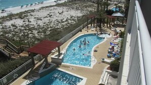 A swimming pool area with a beach view, a separate pool, and a covered seating area. - Beachfront with Beach Setup Included! (Navarre)