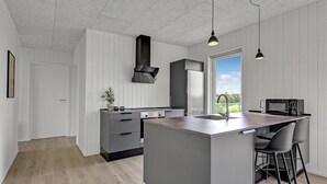Cocina moderna con una isla central, electrodomésticos de acero inoxidable y un amplio ventanal con vistas al exterior.