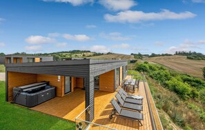Une maison moderne dotée d’une terrasse, d’un espace salon extérieur et d’un jacuzzi.