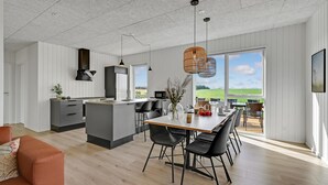 Una cocina moderna con una isla central, sillas negras y una mesa de comedor.