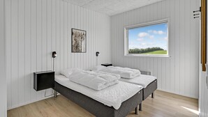 Un dormitorio con dos camas, un ventanal con vistas a zonas verdes y un cuadro en la pared.
