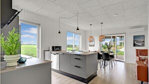 Una cocina moderna con una isla grande, iluminación colgante y vistas al exterior.