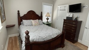 Ein Schlafzimmer mit einem hölzernen Bett, Deckenventilator, Fernseher und Kommode.