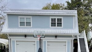 Ein zweistöckiges Haus mit Garage, einem Basketballkorb und einer Treppe, die zur Garage führt.