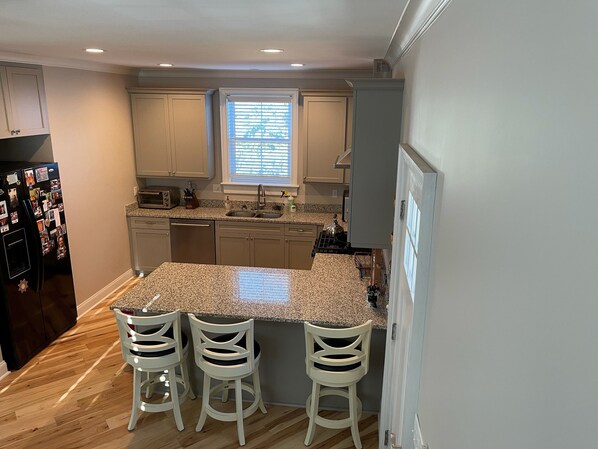 A kitchen with a granite countertop, white cabinets, a built-in oven, and a window with blinds. - Clean, comfortable & quiet Guest house in a terrific location in the Old Village (Mount Pleasant)