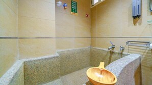 A bathroom with a stone bathtub, a wooden bowl, and a green sign on the wall. - Dingai Holiday Museum (Jiaoxi)