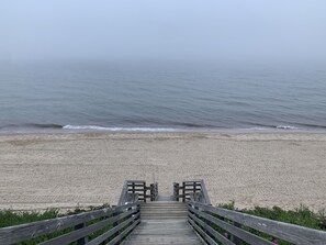 Ein Holzsteg führt zu einem Strand mit Blick auf das Meer.