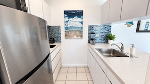 A modern kitchen with a stainless steel refrigerator, a sink with a faucet, and a tiled backsplash.