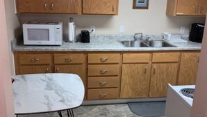 A compact kitchen with wooden cabinets, a white microwave, a coffee maker, and a stove. - Lovely Lovelock Landing (Lovelock)