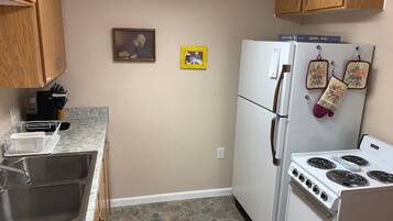 A kitchen with granite countertops, a stainless steel sink, a white refrigerator, and a stove.