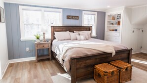 A bedroom with a wooden bed, a nightstand, a dresser, and a wall-mounted shelf. - Lake Winnipesaukee, Weirs Beach, Funspot, Gunstock (Laconia)