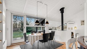 A modern kitchen with a dining area, large windows, and a view of the outdoors.