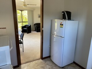 A compact kitchen with a white refrigerator, a coffee maker, and a small countertop.