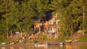 A lakeside lodge with a dock, kayaks, and a building with a porch. - Glamorous lake house on a mountain lake in upstate New York (max of 8 guests) (East Berne)