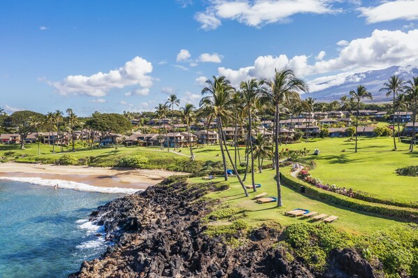 A coastal resort with beachfront properties, a well-maintained lawn, and a view of the ocean.