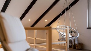 A room with a wooden ceiling, a hanging chair, and a white chair. - Nice home in Slunj with swimming pool (Slunj)