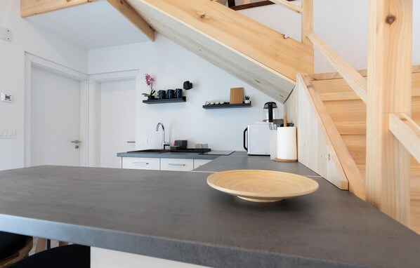 A modern kitchen with a dark countertop, white cabinets, and a wooden ceiling beam. - Nice home in Slunj with swimming pool (Slunj)