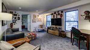 A living room with a sofa, a coffee table, a TV, and a dining table with chairs. - Webster Groves detached Mother-in-Law Suite (Webster Groves)