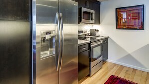 A modern kitchen with stainless steel appliances, a microwave, and a tiled backsplash. - Webster Groves detached Mother-in-Law Suite (Webster Groves)