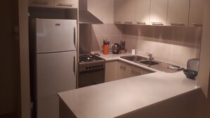 A modern kitchen with a refrigerator, stove, sink, and cabinets.