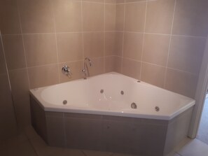 Une salle de bain moderne avec une baignoire sur pieds, des murs carrelés et un espace douche.