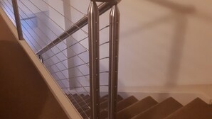 A staircase with a metal handrail and a glass panel.