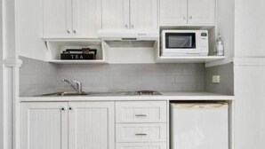 Una cocina con armarios blancos, microondas, lavaplatos y fregadero.