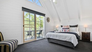Un dormitorio con cama, una silla, una mesita de noche y un ventanal corredero que da a un espacio exterior.