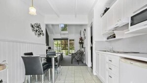 Una cocina moderna con armarios blancos, un comedor con mesa y sillas, y vistas al exterior.