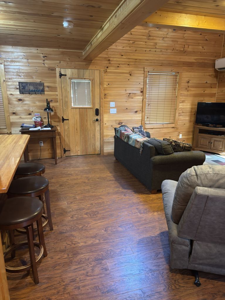 A wooden interior with a dining area, two sofas, and a television.