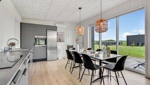 A modern kitchen with stainless steel appliances, a dining area with black chairs, and large windows offering a view of the outdoors. - Pet friendly home in Løgstrup with WiFi (Løgstrup)